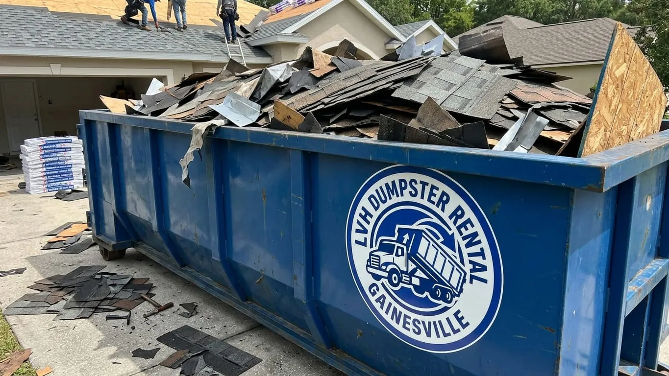 Roofing dumpster rental in Gainesville, GA: a 15 yard roll-off on plywood mats beside a two-story Hall County house during a shingle tear-off, torn shingles and felt loaded flat and low, the container set clear of the eave line and the gutter. Roofing dumpster rental in Gainesville, GA: a 15 yard roll-off on plywood mats beside a two-story Hall County house during a shingle tear-off, torn shingles and felt loaded flat and low, the container set clear of the eave line and the gutter.